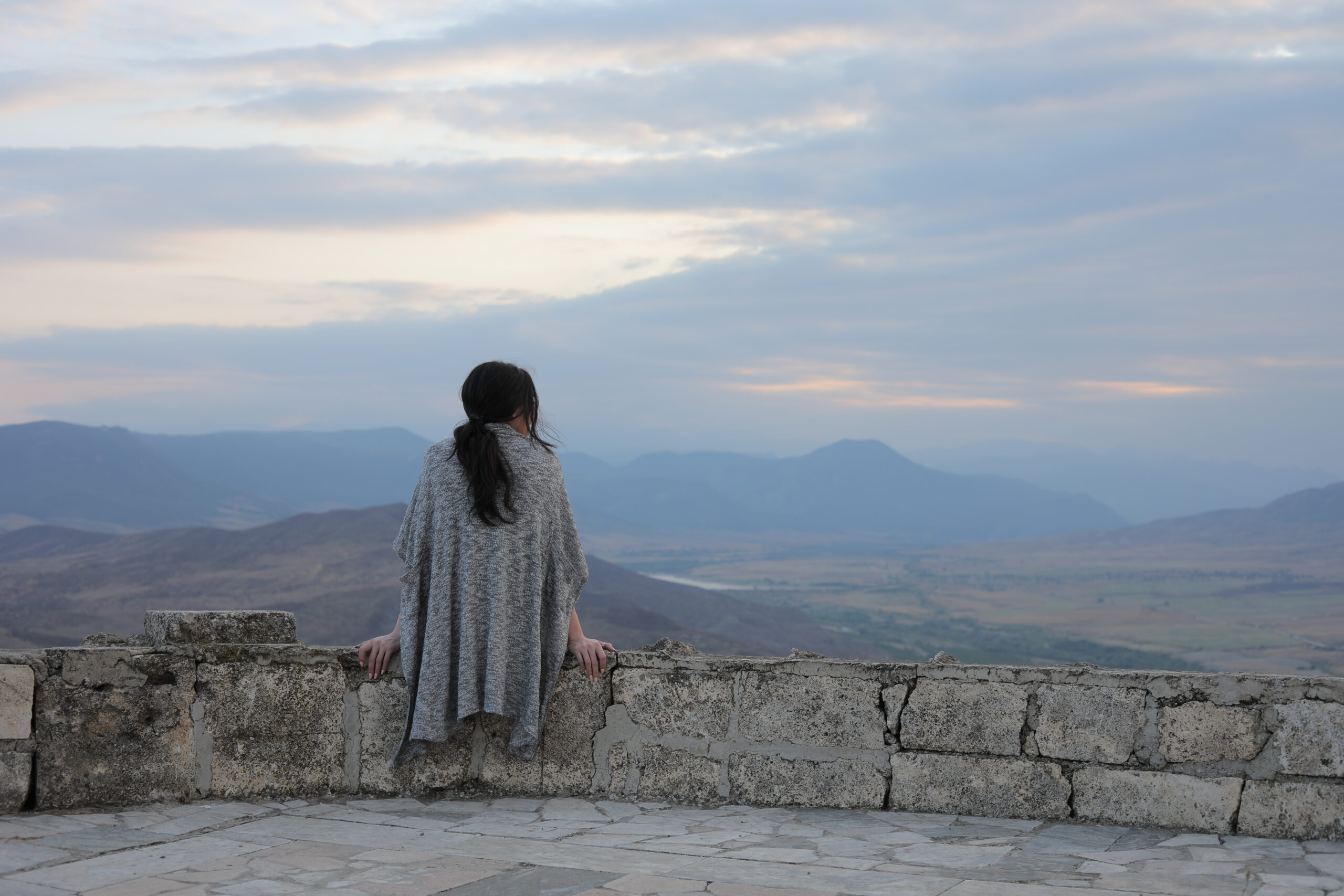 A back view of a young female admiring the beauty of mountains in Karabakh